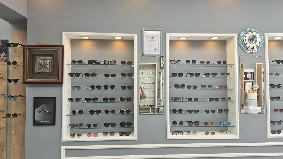Sinan Optik premium wall niches — backlit glass shelves with the sunglasses collection, white moulding frames